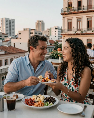 Happy American man and Cuban woman sharing dinner and laughing together at a Havana rooftop restaurant