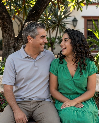 Happy American man and Mexican woman laughing together on a garden bench