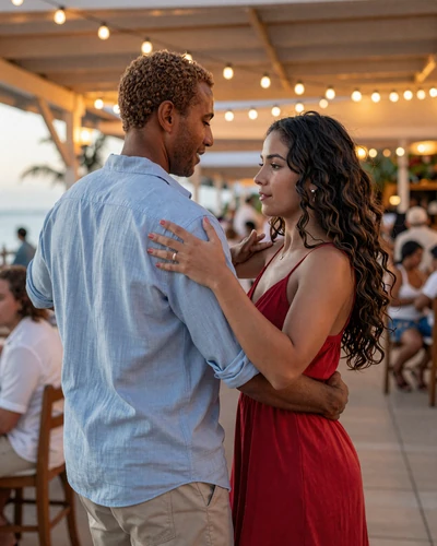 American man and Dominican woman dancing together at an outdoor Caribbean restaurant with string lights